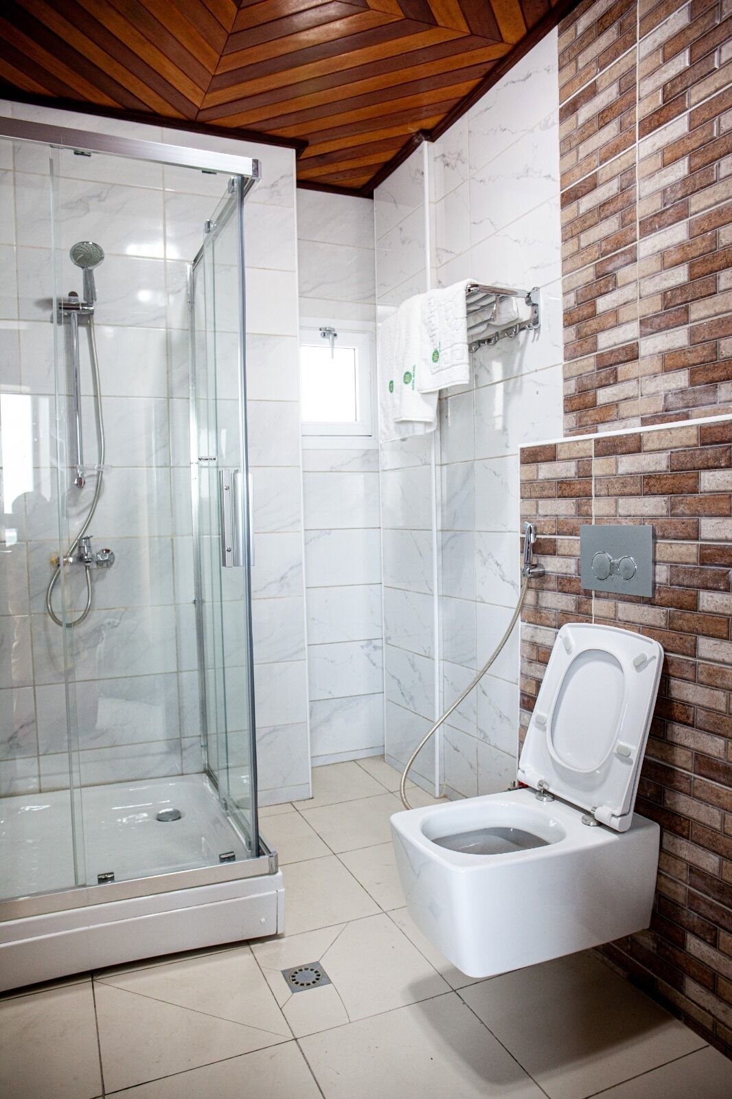 A bathroom with a glass-enclosed shower, a white toilet, and a tiled floor.