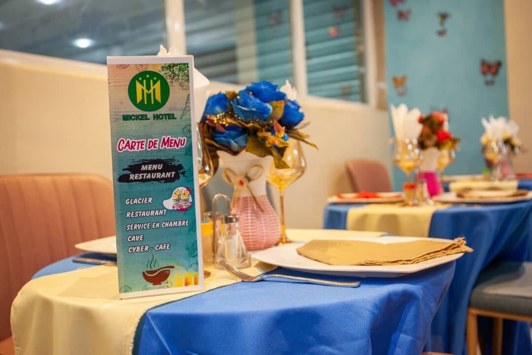 Un menú de restaurante en el Hotel Mickel, con mantel azul y centros de mesa florales.