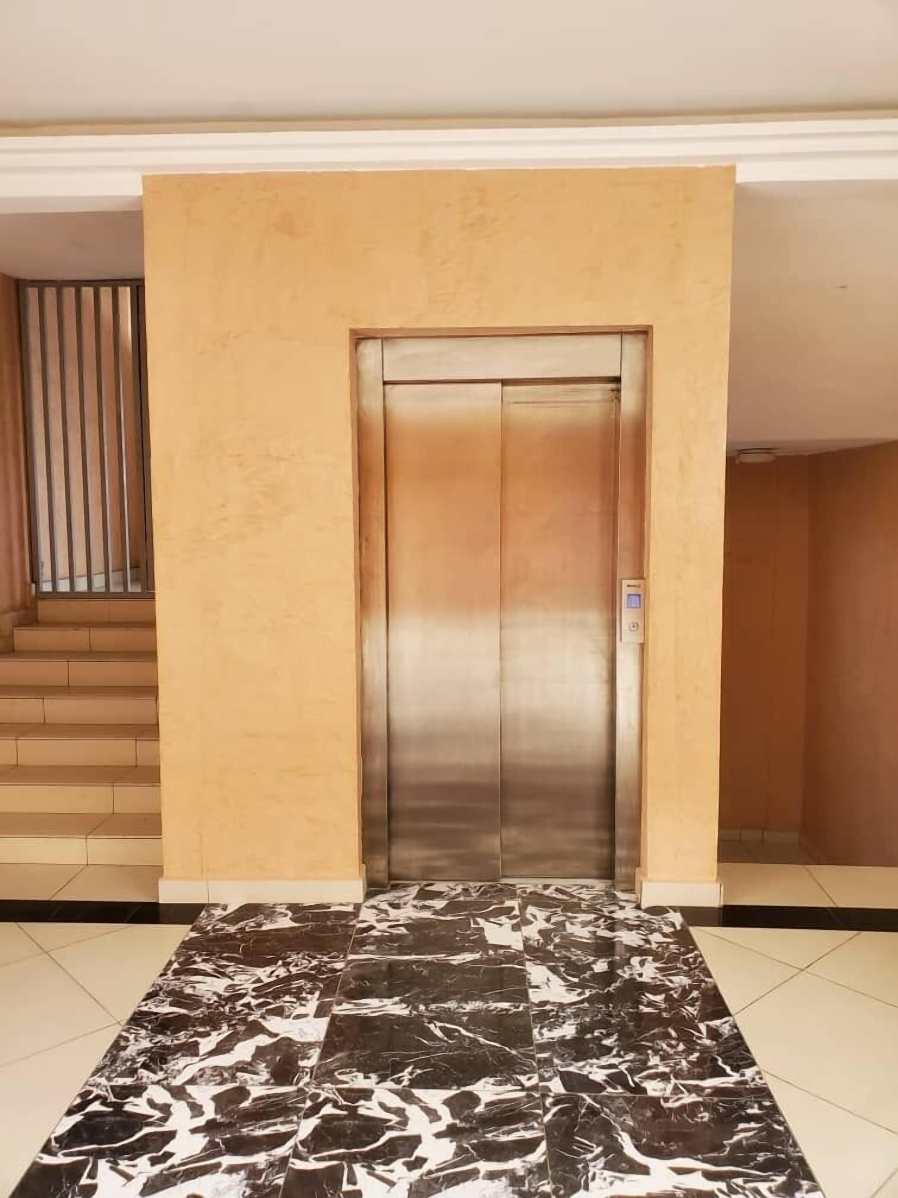 An elevator in a building with a marble-tiled floor.
