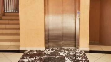 An elevator in a building with a marble-tiled floor.