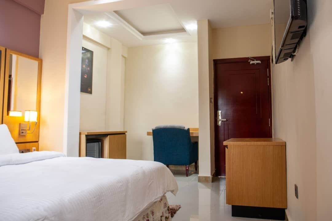 Una camera d'albergo con un letto, una scrivania, una sedia, un armadio e una porta.