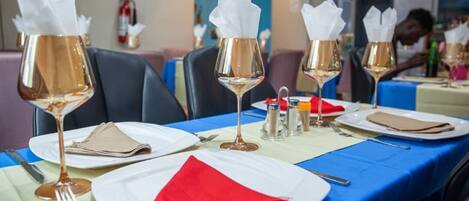 Une table à manger dressée avec des verres à vin, des assiettes et des serviettes.