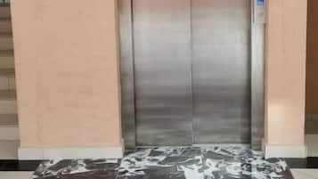Un ascensor con detalles metálicos, un panel de control y un suelo con diseño de mármol.