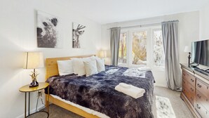 Una camera da letto con un letto grande, due lampade da comodino, una TV e una finestra con tende.