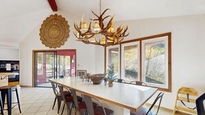 Un'ampia sala da pranzo con una grande isola, sedie moderne e un originale lampadario a forma di corna.
