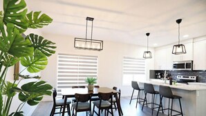 A modern kitchen with a central island, bar stools, and pendant lighting. - Beautiful 3 King Beds|Garage|Airport|Disney+ (Edmonton)