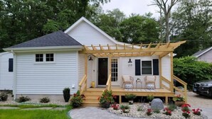 A single-story house with a covered porch, a small patio with outdoor furniture, and a garden with a stone pathway. - Lake Getaway at Coventry Lake! close to Uconn (Coventry)