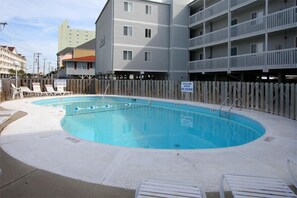 A swimming pool with lounge chairs, a wooden fence, and a sign indicating no diving. - Beachmaster 104-2BR Oceanfront Condo (North Myrtle Beach)