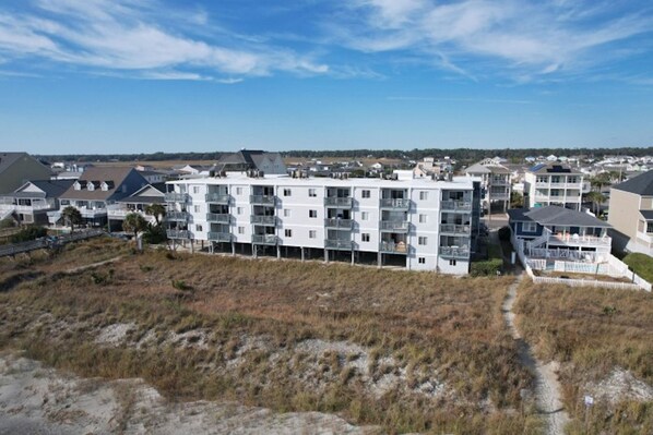 A multi-story residential building with balconies, located near a beach. - Beachmaster 104-2BR Oceanfront Condo (North Myrtle Beach)