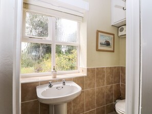 A bathroom with a white sink, a window with frosted glass, and a framed picture on the wall. - Hapton Folly (Waterlooville)