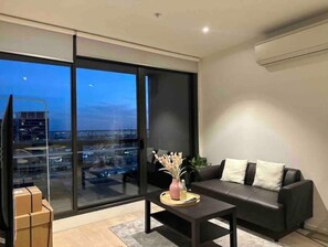 Relax in this stylish living room with a floor-to-ceiling window offering a city view, a comfortable sofa, and a coffee table.