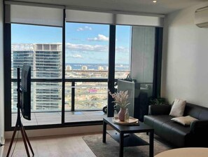 Enjoy a panoramic view of the city and water from this spacious living room with a floor-to-ceiling window.