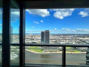 Panoramic city view from a high-rise building, overlooking a river and various buildings.