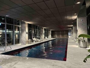 Relax by the rectangular pool surrounded by lounge chairs and glass walls offering a view of the outside.