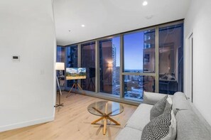 Relax in this stylish living room with a city view, featuring a round table, grey sofa, and floor lamp.