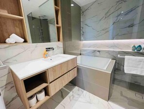 Bathroom features a sink, mirror, and separate bathtub with a glass enclosure.