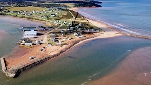 Vue aérienne d’une ville côtière avec une plage, des maisons et une jetée.
