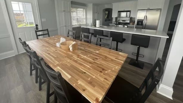 Une cuisine moderne avec un îlot central en bois, des meubles blancs et des appareils électroménagers en acier inoxydable.
