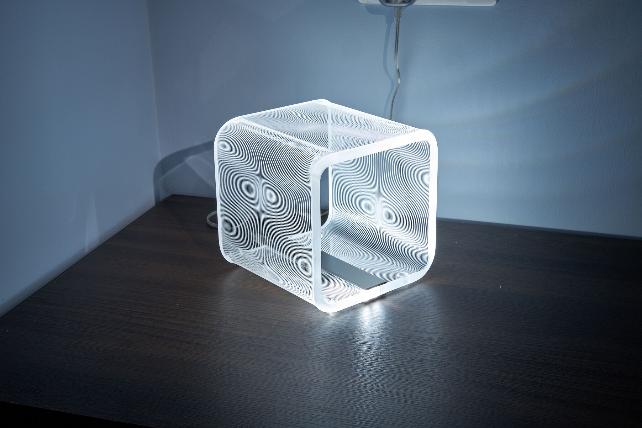 A transparent cube with a geometric pattern on a wooden surface.