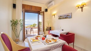A dining area with a table set for breakfast, a potted plant, and a view of the outdoors. - B&B Torre Talao (Scalea)