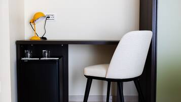 A compact workspace with a desk, a chair, a small black cabinet, and a yellow desk lamp.