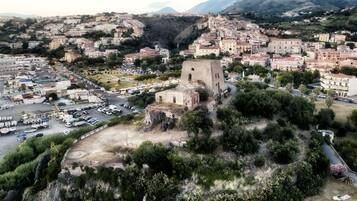 Vista aérea de un pueblo con una imponente torre histórica, una plaza central con coches aparcados y edificios residenciales circundantes.