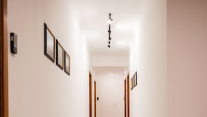 A hallway with a polished floor, framed pictures on the walls, and a patterned rug at the end. - B&B Torre Talao (Scalea)