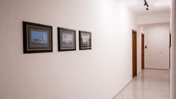 Un corridoio con tre quadri appesi al muro e un pavimento lucidato.