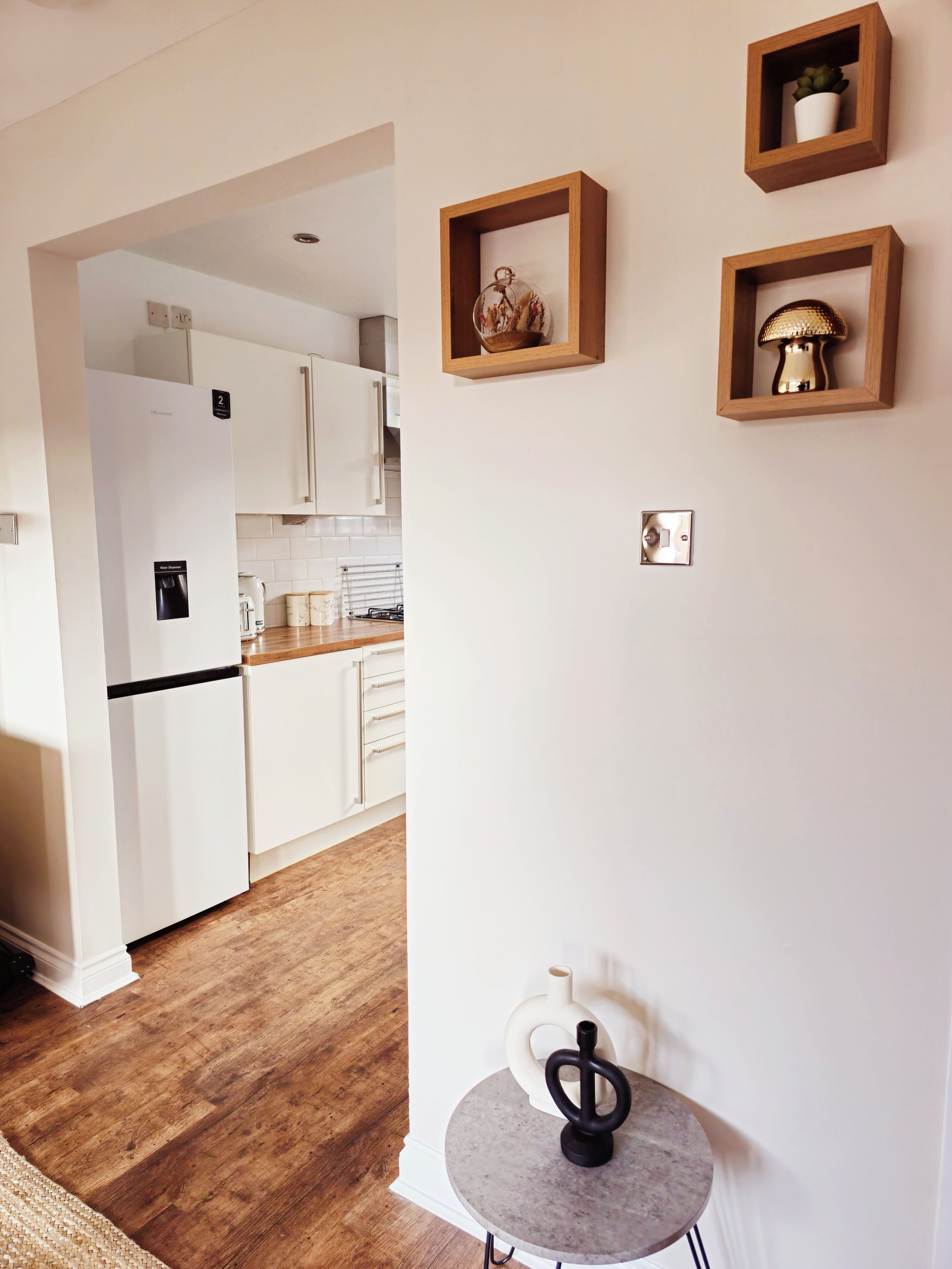Eine moderne Küche mit weißen Schränken, einer Holz Arbeitsplatte und einem runden Tisch mit einer Vase.