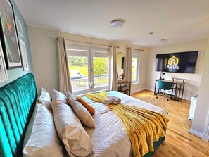 Ein Schlafzimmer mit Bett, Schreibtisch, Stuhl und einem Fernseher mit dem AirUs-Logo.
