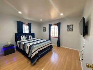 Relax in this serene bedroom with a large bed, striped bedspread, and two windows with curtains.