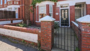 A red brick house with a black gate, white trim, and a small garden area.