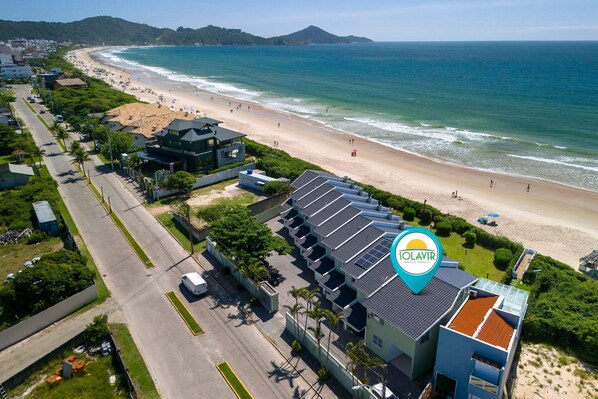 A coastal hotel with a beach view, multiple-story buildings, and a parking area. - Residencial Guilhermina (Bombinhas)