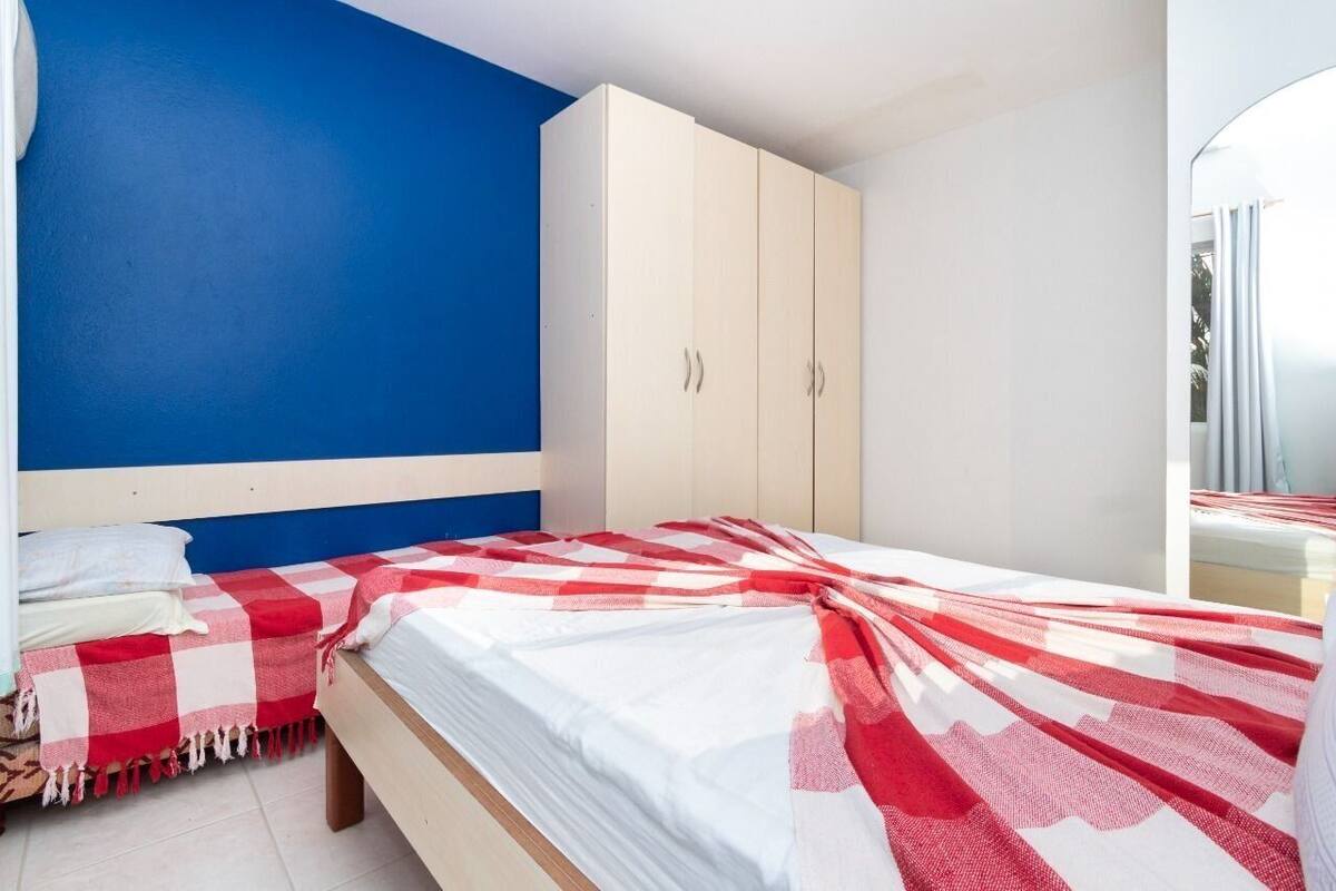 A bedroom with a bed, a wardrobe, and a blue wall.