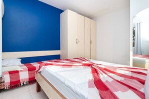 A bedroom with a bed, a wardrobe, and a blue wall. - Residencial Guilhermina (Bombinhas)