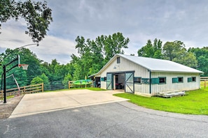 A single-story building with a gabled roof, a large open garage door, and a basketball hoop to the left.