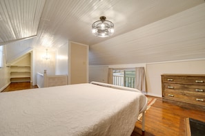 A bedroom with a bed, a dresser, a staircase, and a ceiling fan.