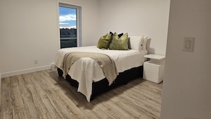 Un dormitorio con cama, mesita de noche y ventana con vistas.