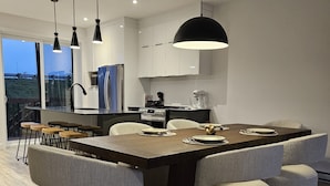 Una cocina moderna con una isla central, luces colgantes y vistas al exterior.