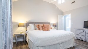 Een slaapkamer met een groot bed, twee nachtkastjes met lampen, een dressoir en een televisie.