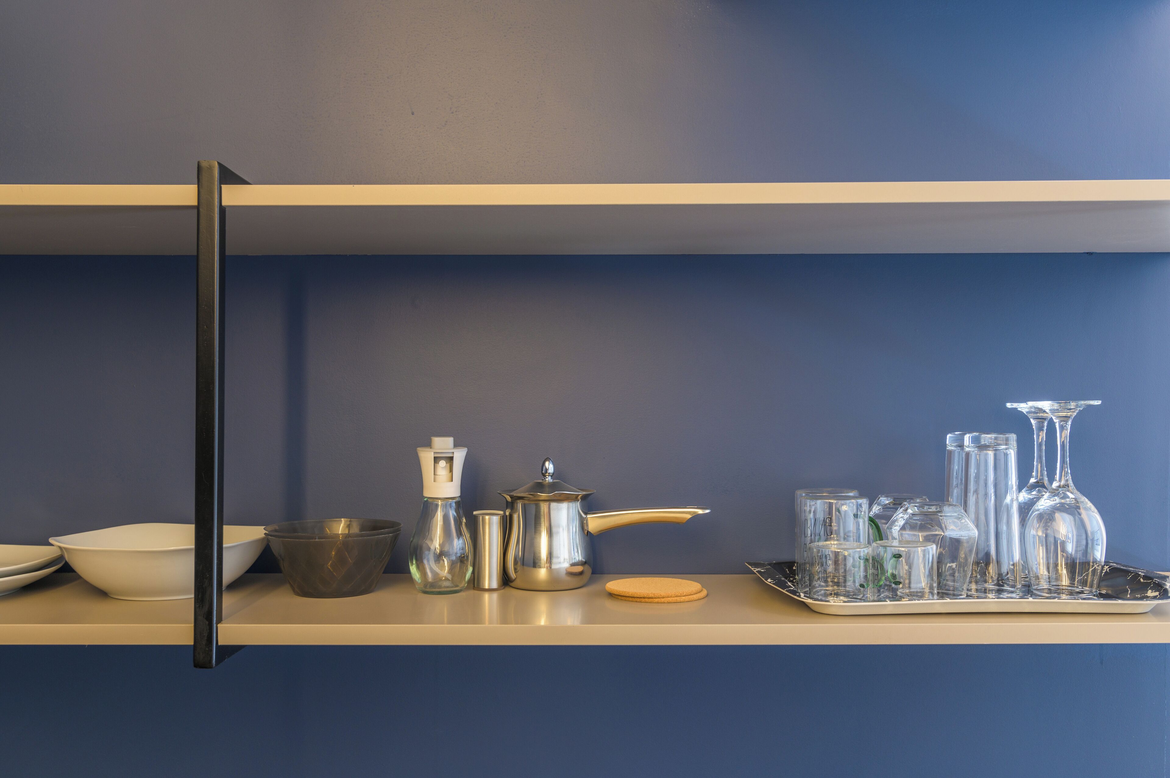 Een keukenkastje met verschillende glazen, een koffiepot en een dienblad met glaasjes.