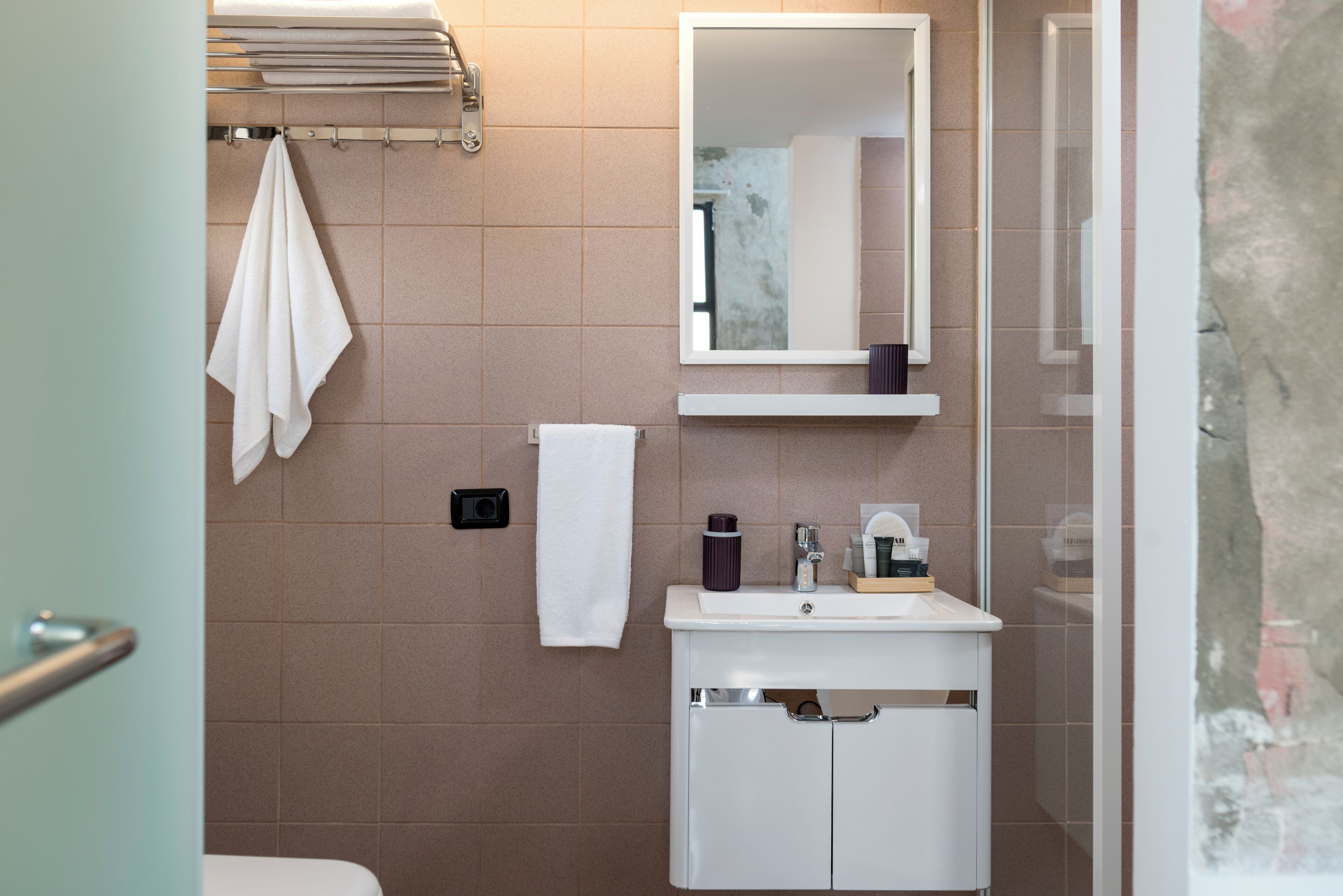 Un baño con inodoro, lavabo, espejo y perchero para toallas.