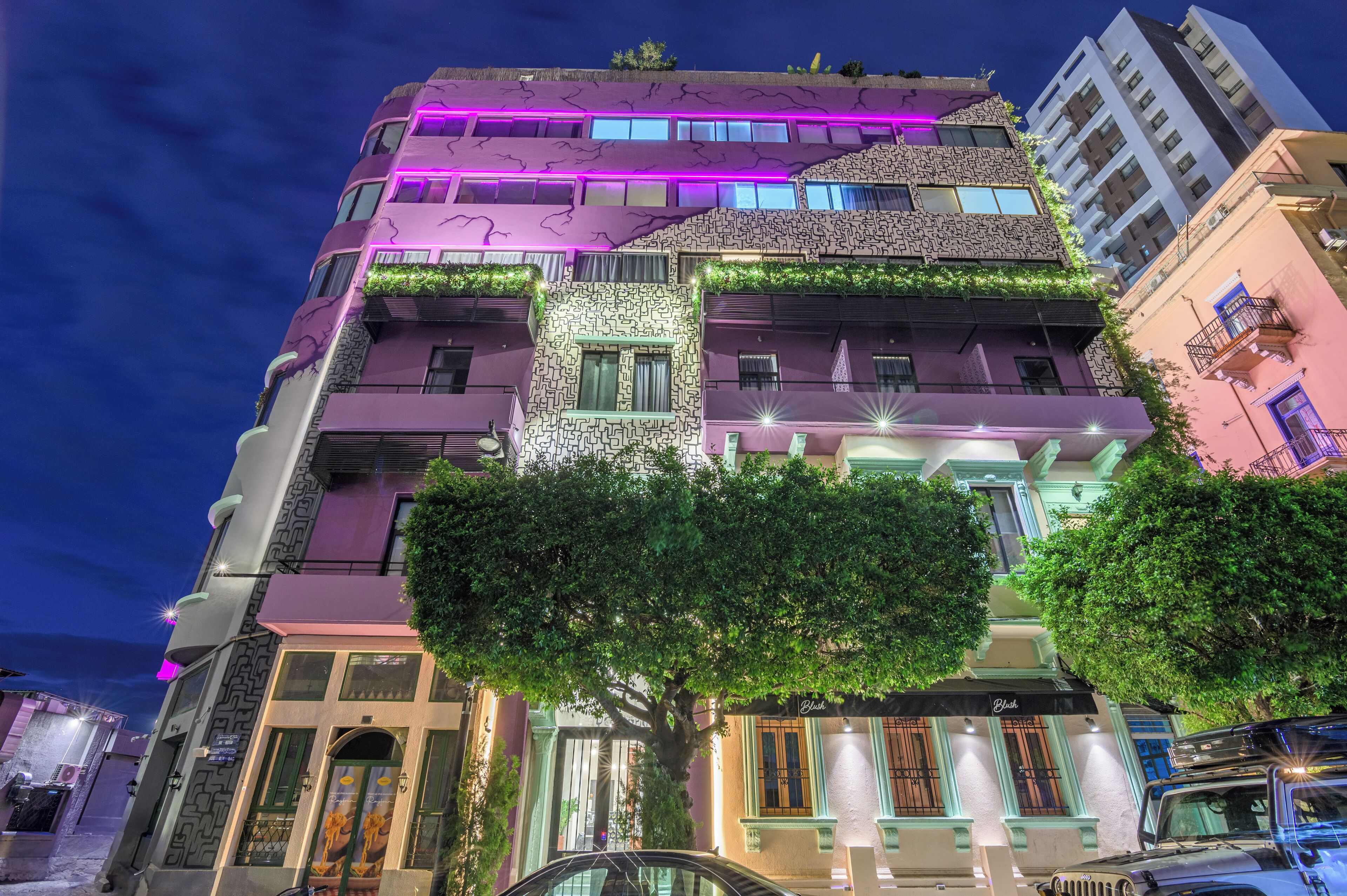 Un edificio de varios pisos con una fachada singular, que combina diferentes estilos arquitectónicos e iluminación vibrante.