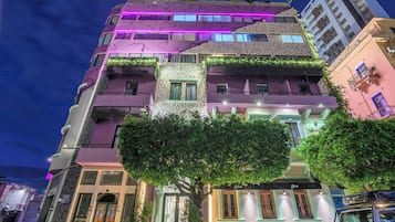 Un edificio de varios pisos con una fachada singular, que combina diferentes estilos arquitectónicos e iluminación vibrante.