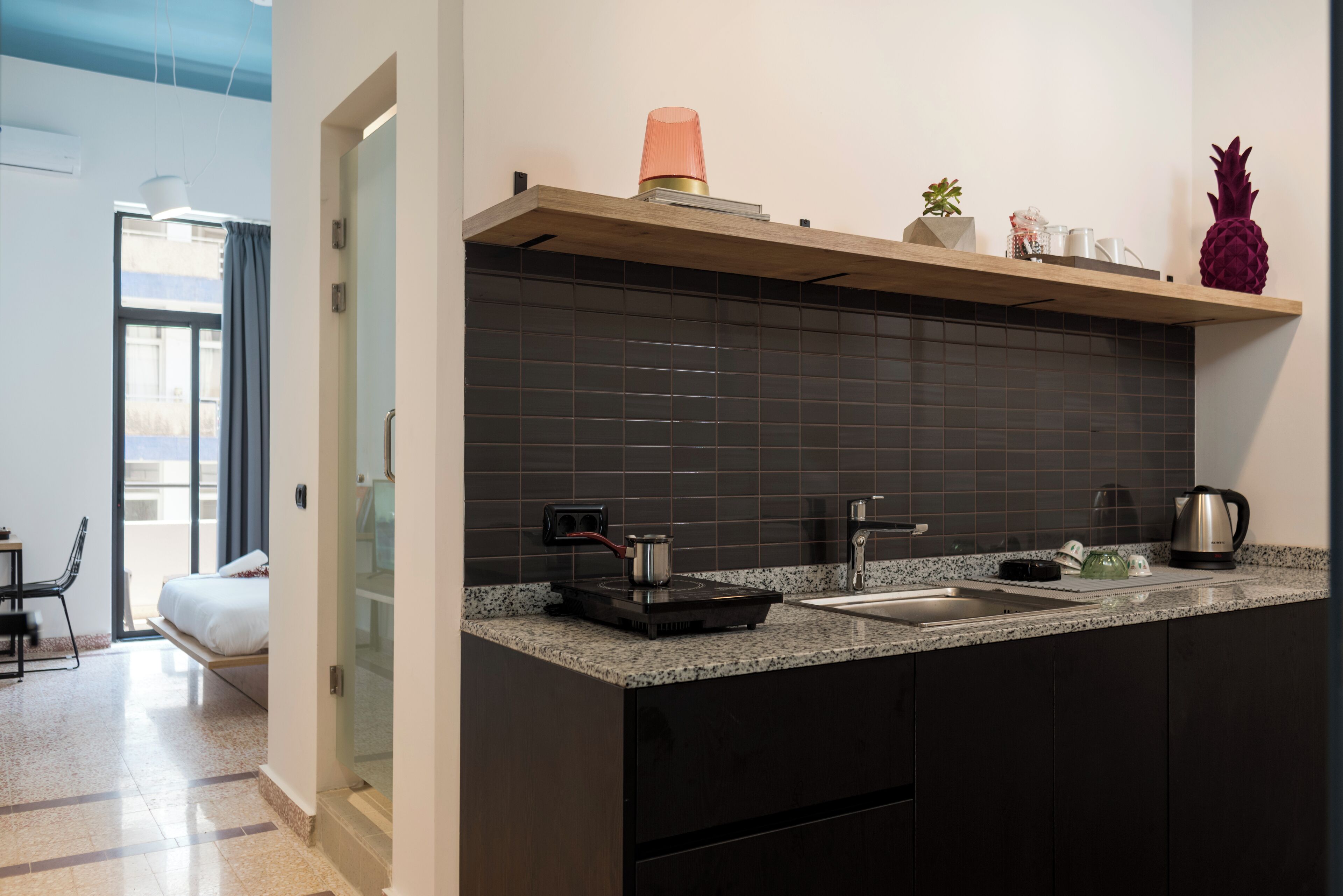 A modern kitchen with dark tiles, a wooden countertop, and a built-in sink.