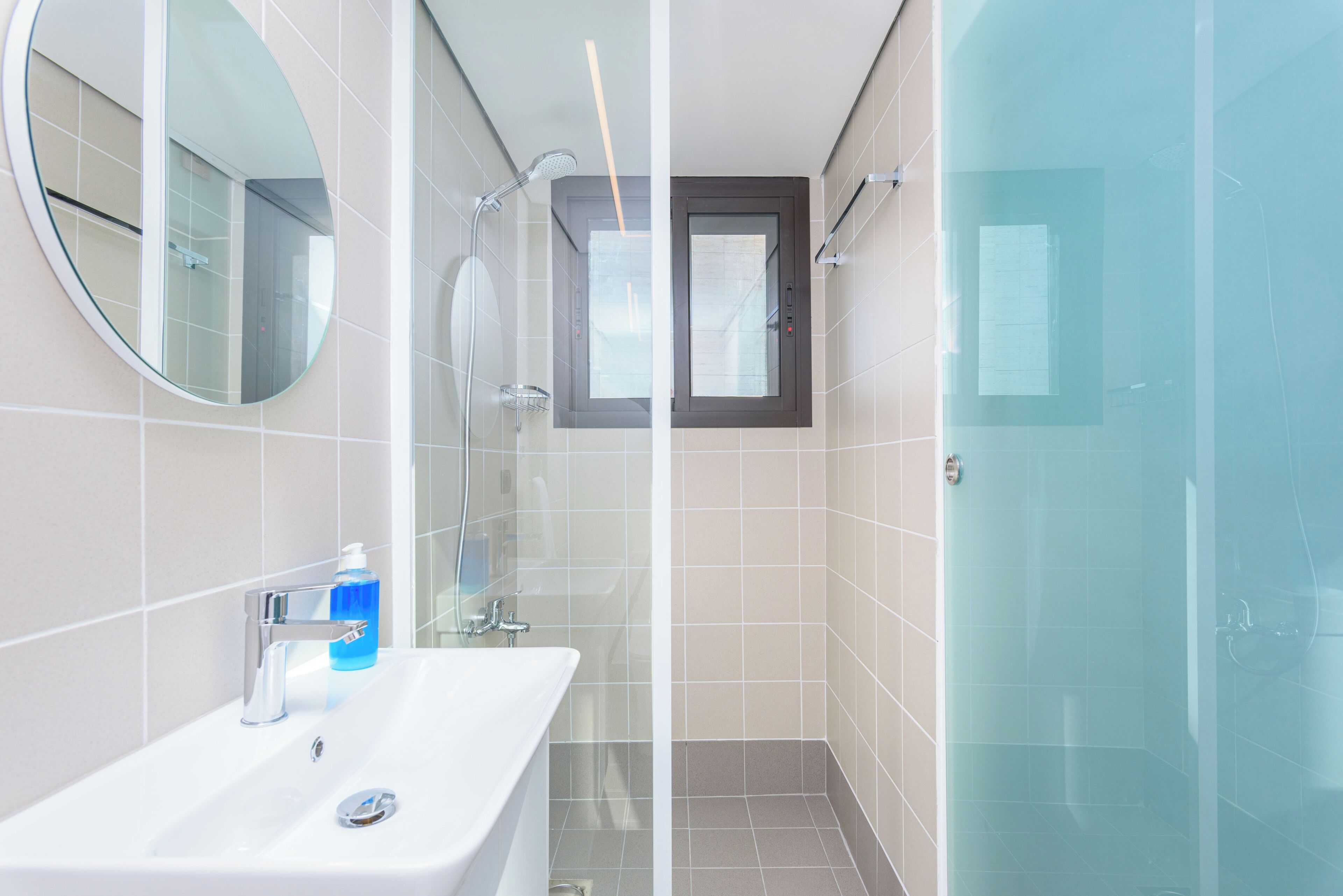 A modern bathroom with a glass shower enclosure, a white sink with chrome fixtures, and a mirror.