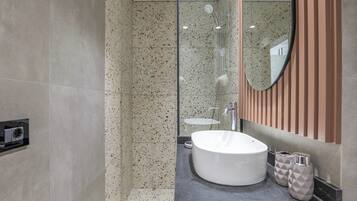 Un baño moderno con un lavamanos independiente, una cabina de ducha de vidrio y un espejo con diseño de panel de madera.