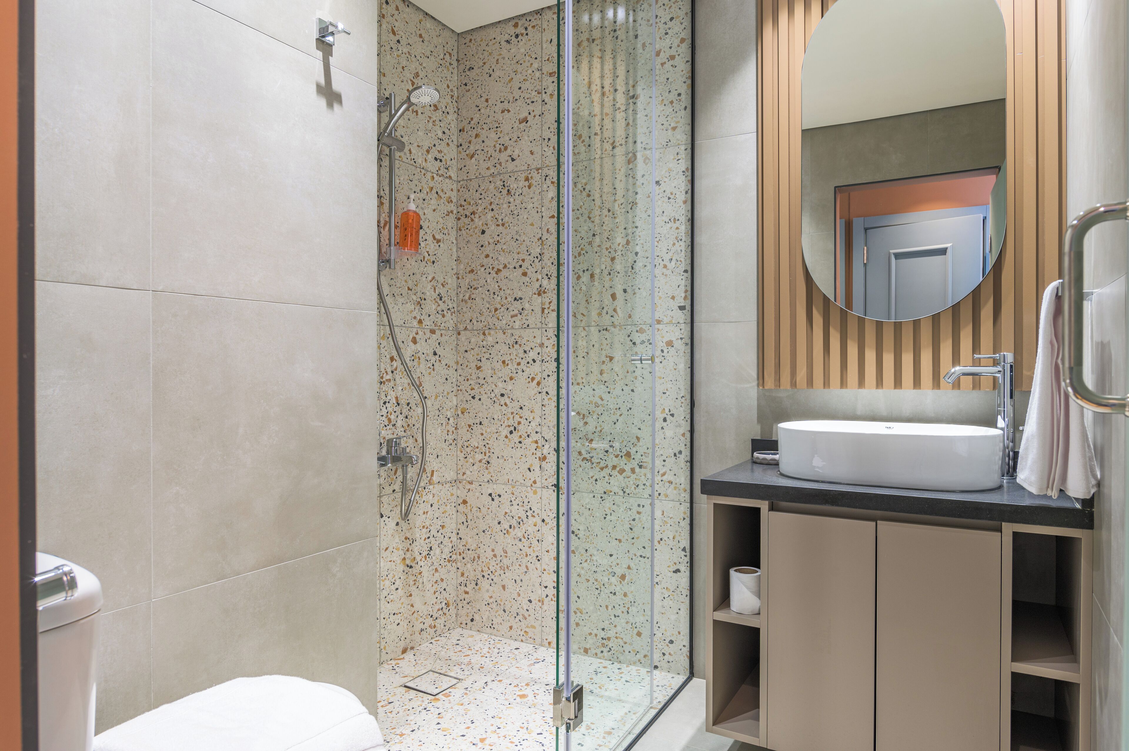 A modern bathroom with a glass-enclosed shower, a white sink, and a mirror above the sink.