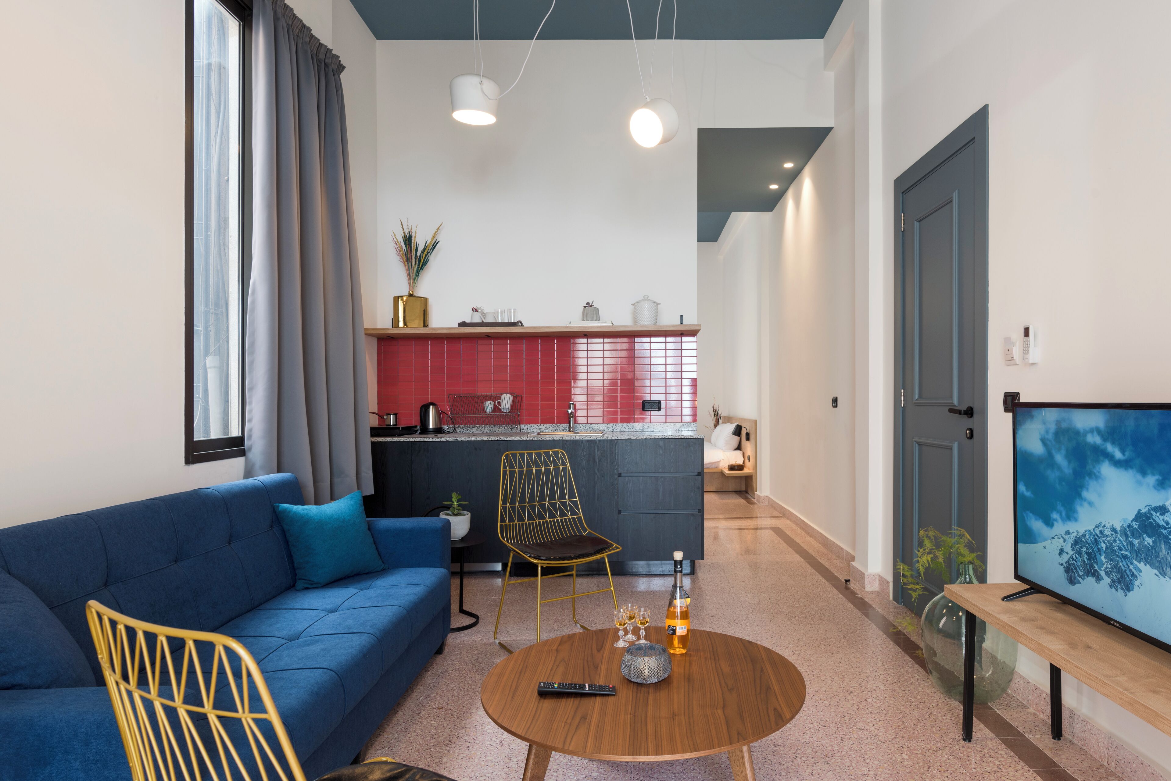 Een moderne woonkamer met een blauwe bank, een houten salontafel en een tv op een houten dressoir.