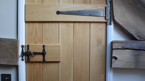 A wooden door with a metal latch and a sliding mechanism, set in a room with a sloped ceiling and wooden beams. - Cowshed near Abergavenny in the Black Mountains (Abergavenny)